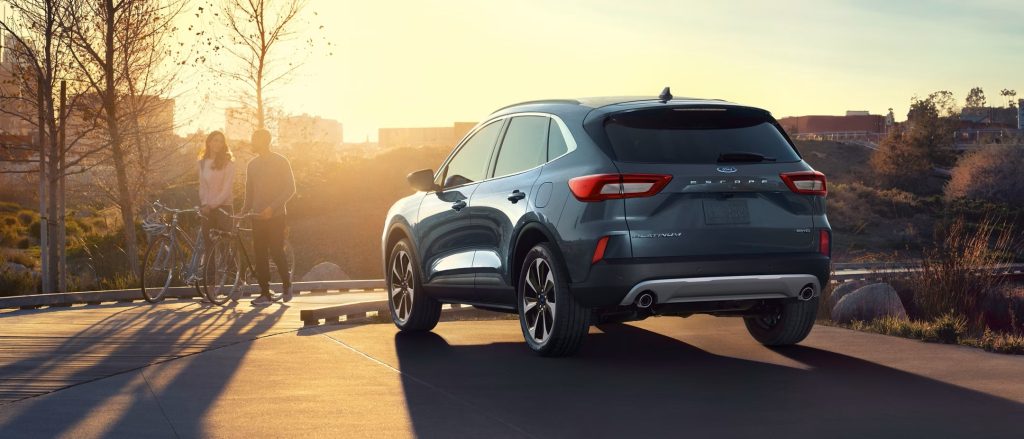"Ford Escape Platinum parked by a scenic pathway with a couple standing beside their bicycles during sunset.